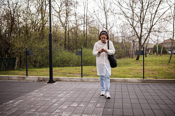 istock Young woman talking on her smartphone while walking through a city 2209538033