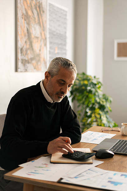 Mature businessman calculating finances at desk