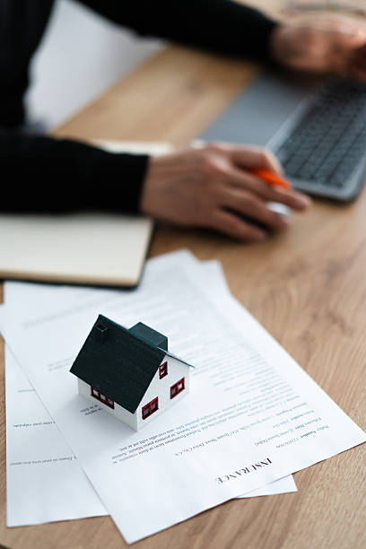 istock Real estate agent working on insurance policy with house model on documents 2209539587
