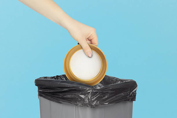 istock throw a cap from a plastic bottle into the trash bin, hold a cap from a plastic bottle in your hand in front of a trash can, plastic recycling concept 2209541786