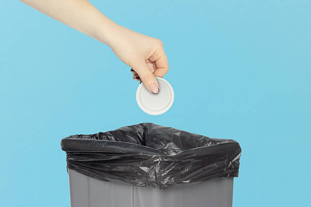 istock throw a cap from a plastic bottle into the trash bin, hold a cap from a plastic bottle in your hand in front of a trash can, plastic recycling concept 2209541800