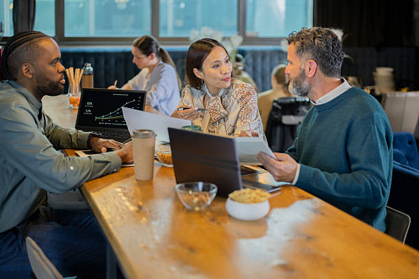 istock Diverse Business Team Collaborating in Bright Office Coffee Corner with Laptops and Documents 2209543311