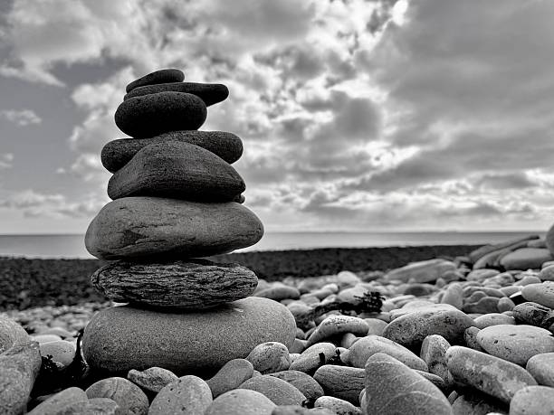 A vertical stack of smooth pebbles stands on the shingle at Hualien's Pacific shoreline with soft waves in the background. Concept image for balance, zen, stability, mindfulness and wellness; no people.