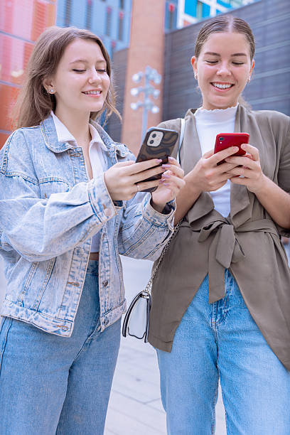 istock Happy Caucasian friends using smartphones outdoors in a modern urban setting 2209544405
