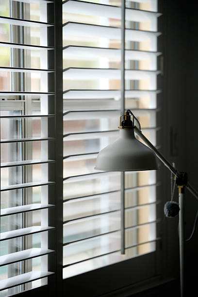 istock White floor lamp illuminating window with venetian blinds partially closed 2209545937