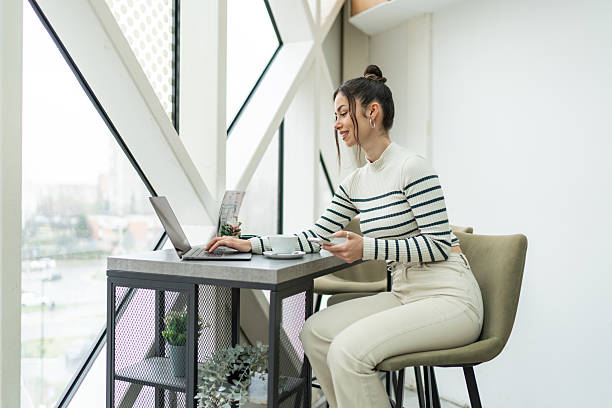 istock Smiling woman working remotely in bright modern cafe 2209546738