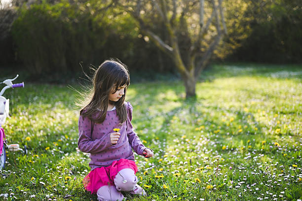 Young girl picking dandelions in a field on a sunny spring day