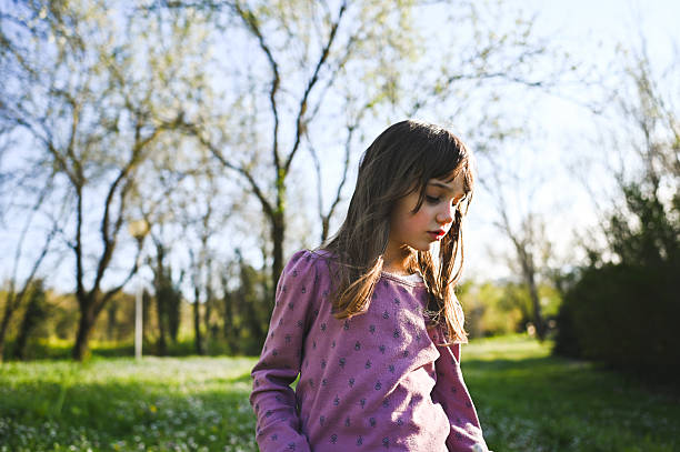 Young girl of 5 biting her nails outside