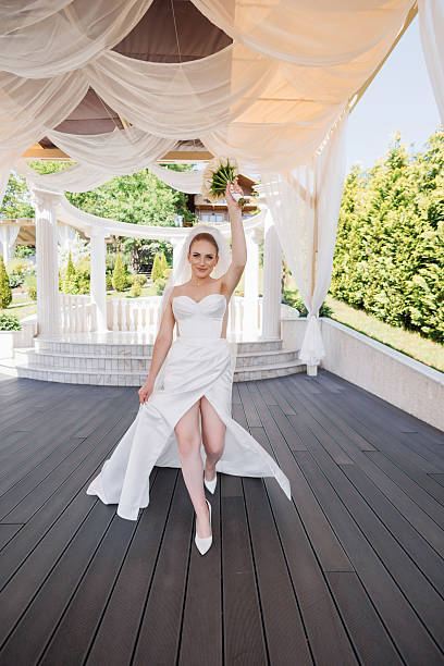 istock A bride is walking down a wooden walkway with a bouquet in her hand 2209549580
