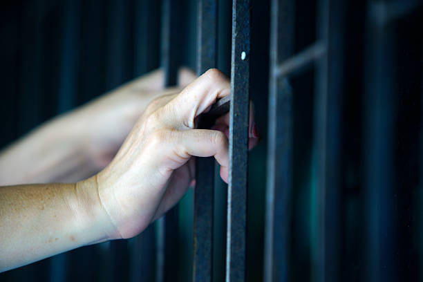 Close-up of Hands Gripping Metal Bars in Dim Light Environment