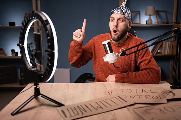 istock Crazy conspiracy theorist blogger streaming live at home using smartphone and ring light, showing idea gesture with finger-up 2209558162