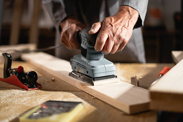 istock Close up of carpenter's hands using electric sander while working in carpentry workshop 2209558301
