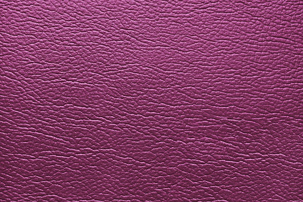 Glossy structure of genuine leather, natural skin surface with embossing pattern. Artifical pink colored  leatharette close up, macro texture. Background, wallpaper, backdrop.