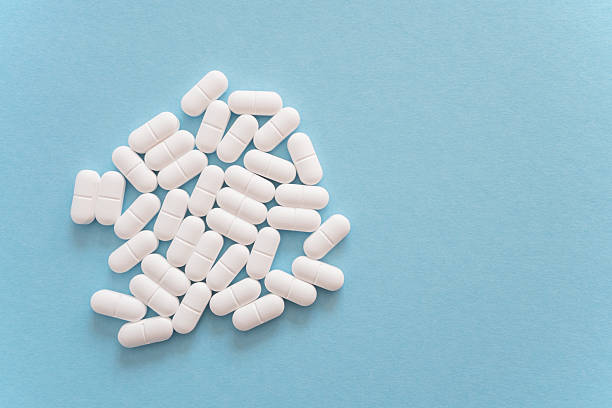 istock White tablets or pills on the blue background. 2209560455
