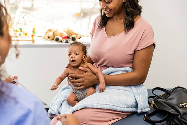istock Mother Holding Baby at Doctor's Office Visit 2209560504