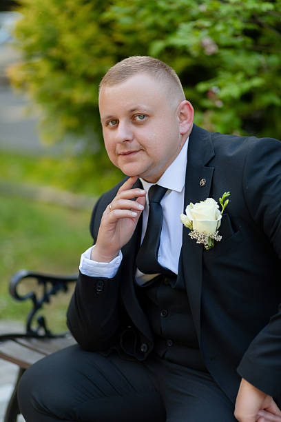 istock A man in a suit and tie sits on a bench with a white flower in his lapel 2209566489