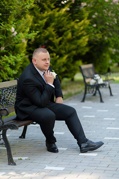 istock A man in a suit sits on a bench with a flower in his hand 2209566504