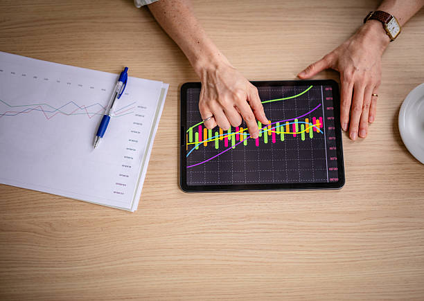 Colleagues engage in a productive discussion, analyzing charts on a tablet while collaborating on business strategies. The atmosphere is one of teamwork and positive energy, showcasing expertise.