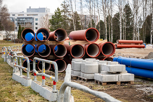 istock Red construction pipes stacked on wooden pallets at a construction site 2209575464