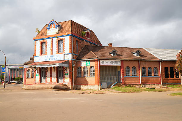 Antsirabe, Madagascar - 28 April, 2025: Historical cultural monument, old colonial house where postal services are provided. In front of it is empty road and in background cloudy sky.