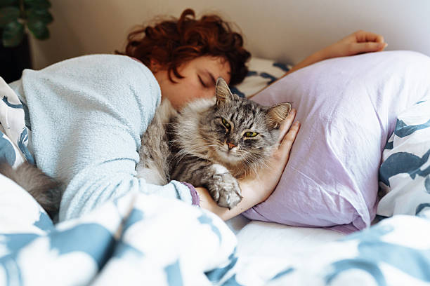 istock sleeping young woman on bed with pet cat 2209580111