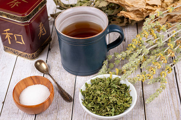 Green tea or herbal tea with cup, sugar and dry herbs