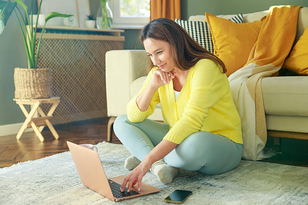 istock Young woman using her laptop while sitting on the floor at home 2209580810