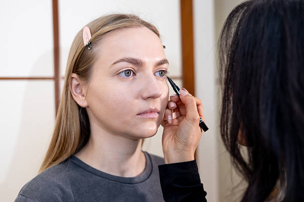 istock Makeup artist applying cosmetics to model in home studio 2209581092