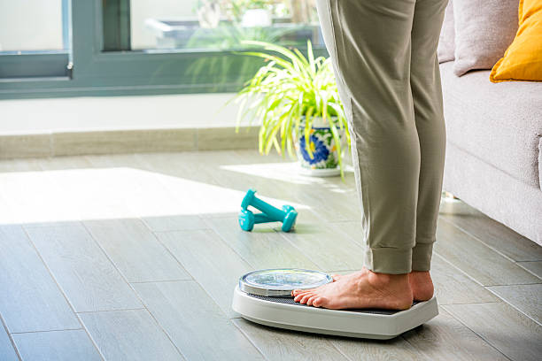istock Woman standing on bathroom scale 2209582067