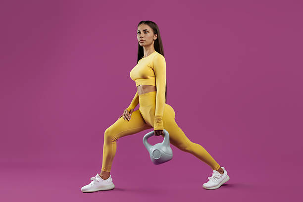 istock Fit young brunette woman doing functional exercises with gray kettlebell over purple background 2209583563