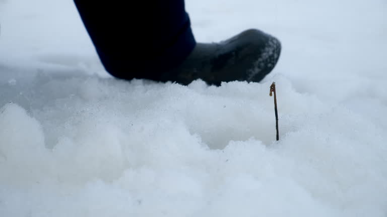 Ice fishing in action fisherman catch fish pulls fishing rod out of cold water.