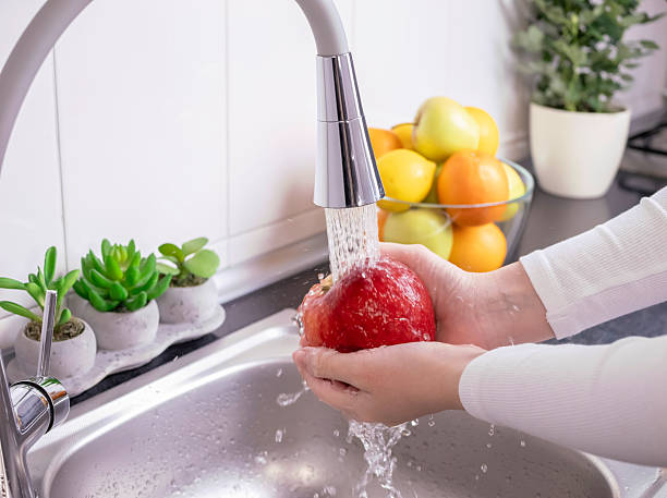 istock Woman hands washing fresh red apple in the kitchen 2209587099