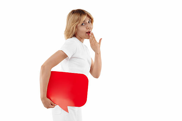Cute blonde woman holding red blank speech bubble over white background.