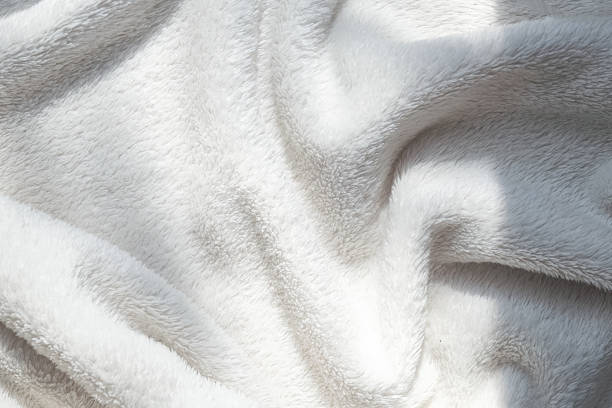 istock White soft eco-fur textile and textured pleats in sunlight, beautiful shadows 2209591716