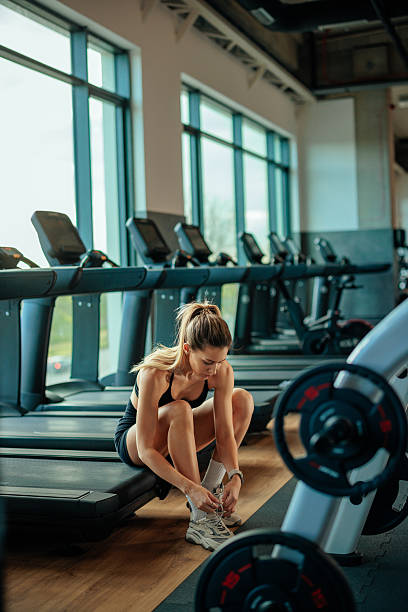 istock Young woman tying shoelaces before exercising in gym 2209591981