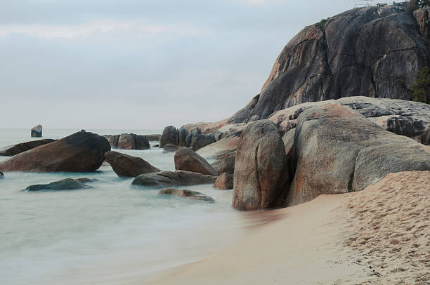 Serene coastal landscape featuring smooth granite boulders on a sandy beach, creating a tranquil atmosphere at dawn, Ko Samui, Thailand