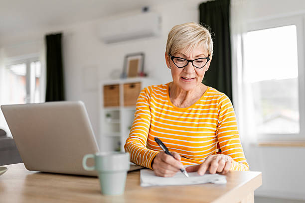 istock Elderly Female Writing Bills and Budget Plans Remotely 2209595987