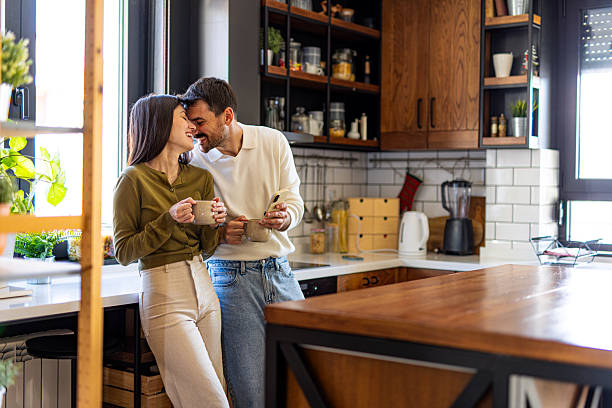 istock Romantic couple drinking coffee and sharing tender moment in modern kitchen 2209600332
