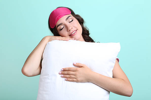 istock Beautiful girl with sleeping mask and white pillow on mint background 2209601348