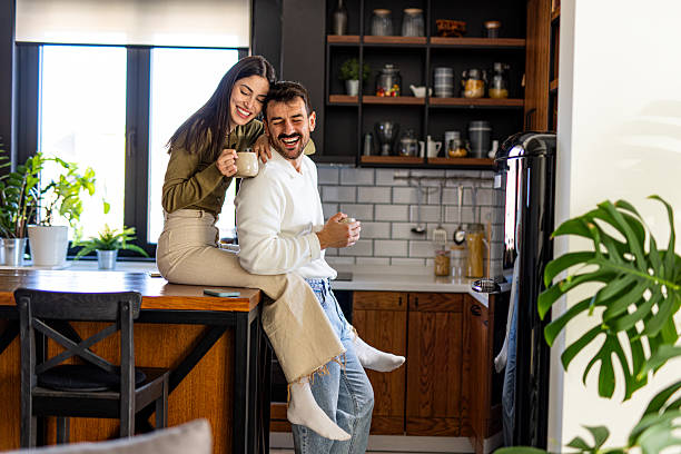 istock Happy couple laughing and drinking coffee in kitchen 2209601758
