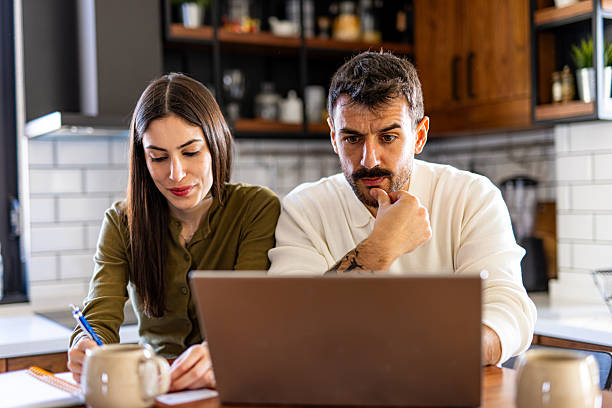 istock Couple managing domestic finances using laptop and taking notes at home 2209602236