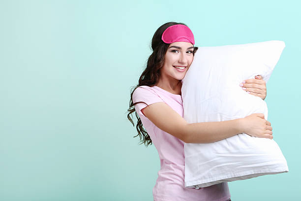 istock Beautiful girl with sleeping mask and white pillow on mint background 2209602558