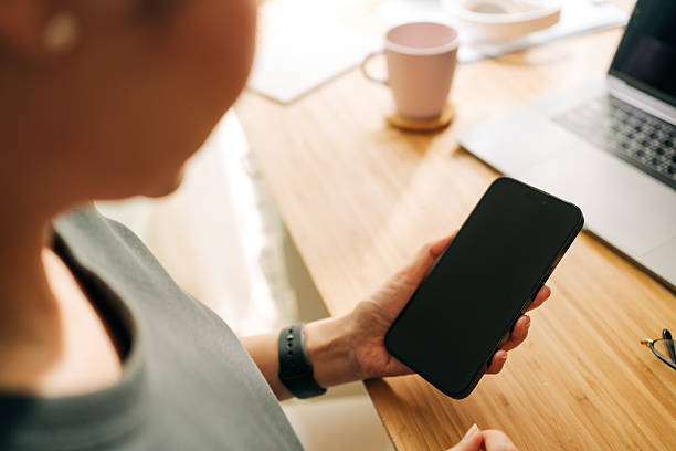 istock Asian female browsing ecommerce site on mobile phone while working remotely from home 2209602837