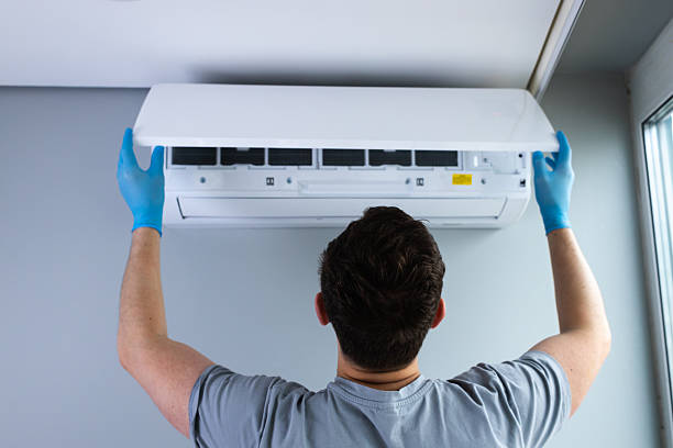 istock Technician Installing or Maintaining Air Conditioner Unit on Wall Amidst a Bright, Contemporary Room and Performing Professional HVAC Services with Care and Precision for Optimal Performance 2209606609
