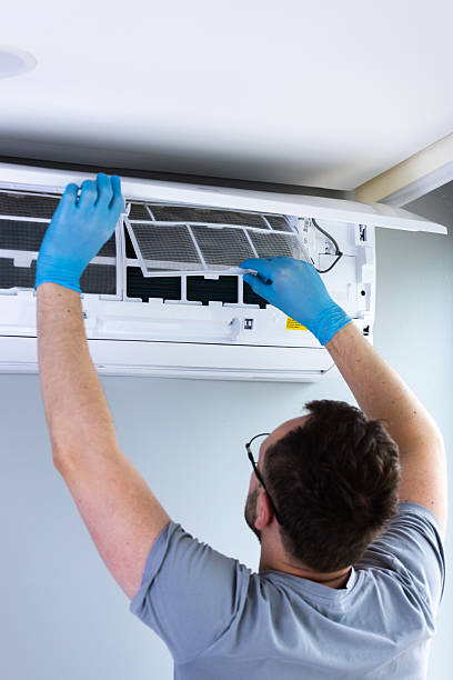 istock Technician Performing Routine Maintenance on Air Conditioning Unit with Protective Gloves in a Bright and Clean Environment for Optimal Device Performance 2209607059