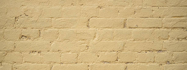 istock A weathered yellow brick wall displays a rough texture with small cracks and uneven surfaces. The warm afternoon light enhances its colors, showcasing its unique characteristics and history 2209607279