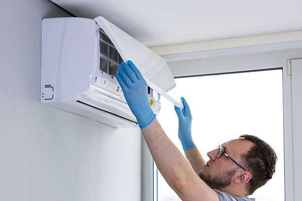 istock A Technician Performing Maintenance on a Wall-Mounted Air Conditioner Unit in a Bright Room with Large Windows, Wearing Blue Gloves and Focusing on Cleaning the Filter 2209608834