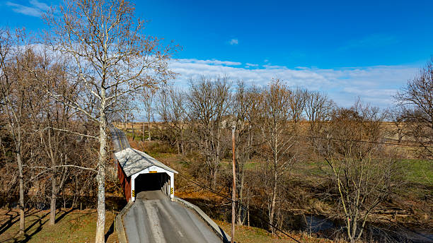 istock Scenic View of a Historic Covered Bridge Spanning a Tranquil River on a Bright Fall Day 2209611712