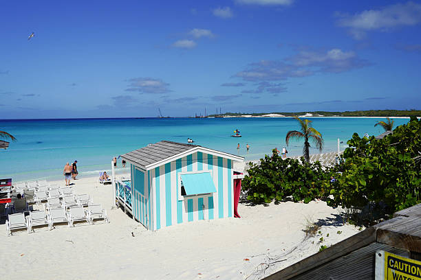 A thatch covered sitting area in the Exuma Islands of the Bahamas is decorated with flotsam from the shore including buoys, floats, and washed up shoes.