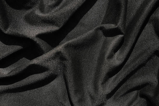 istock Black fabric with soft folds and slight shining effect. Close-up texture, abstract background. Luxurious wallpaper 2209612111